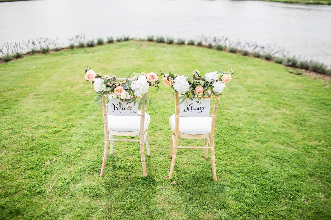 Romantic ceremony chairs dressed with roses and hydrangea by the water